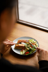 Girl Eating Fried flapjacks with Chicken and Salad of Greens, Cucumber, Tomato and Pumpkin Seeds