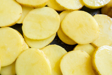  raw potato slices in a tray ready to be baked close-up