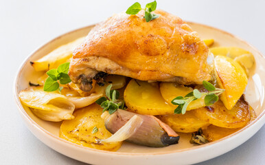 roasted chicken thigh with potatoes, lemons, and shallot onions in a dish close-up