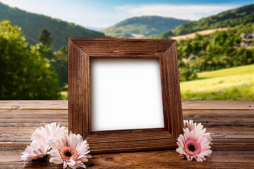 Generated Image Rustic wooden picture frame with blank space, surrounded by flowers on a wooden table with scenic nature background, perfect for outdoor, wedding, or seasonal design mockups.