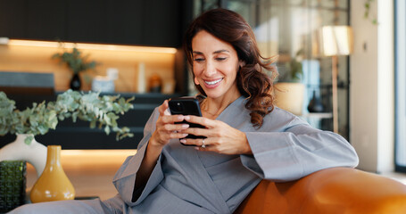 Home, relax and woman on couch smartphone and smile with message to contact, social media and meme. Happy, apartment and person on sofa, cellphone and internet with chatting or email notification