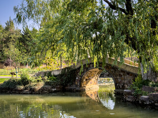 Tranquil Stone Bridge Amidst Lush Greenery and Reflective Waters