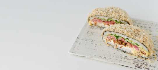 Sushi burger with tuna, cucumber, onion, cheese and rice in a nori with a crispy crust on a white plate. Hybrid food concept. Horizontal orientation. Selective focus. Copy space. Bunner