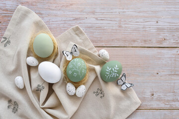 Stylish decorated easter eggs on linen cloth on a light wooden background. Top view. With space for your text