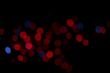 Blurred red and blue lights create a bokeh effect against a dark backdrop. The abstract and colorful lights provide a festive and decorative visual.