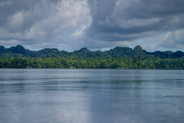Tropical forest meets calm ocean under dramatic clouds on a remote island coast