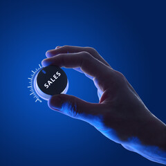 Businessman adjusting glowing dial labeled SALES against dark blue background in neon. Control and...
