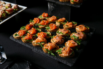 A tray of appetizers with smoked salmon on a black table