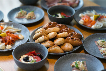 A dining table beautifully topped with plates of delicious meals Russian pirogi