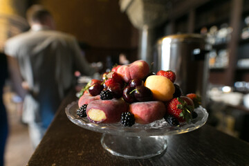 A beautiful glass bowl overflowing with vibrant fruit and berries on a table