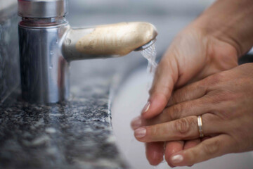Close up of human hand washing hand on sink.