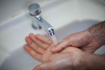 Close up of human hand washing hand on sink.