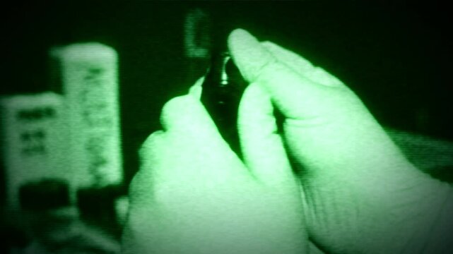 Night vision green color scale filter. Hands rolling an old school retro camera film onto a film roll in a dark room