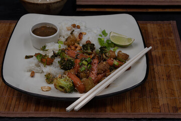 Vegan stir fry and rice on square white plate with chopsticks