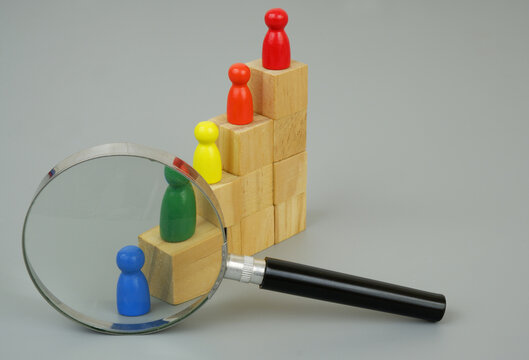 Review achievements of goals and ranking people concept. People figures as workers on stair made of wooden cubes under magnifying glass.