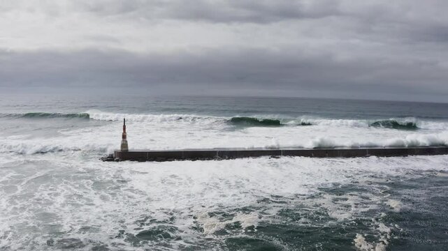 Huge waves crashing over Breakwater during winter storm Atlantic waves washing the lighthouse on Praia da Aguda sandy beach at Aguda settlement near Porto, Portugal. Incredible 4K flying drone video.