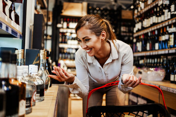 Beautiful young and elegant woman buying some healthy food and drink in modern supermarket or grocery store. Lifestyle and consumerism concept.