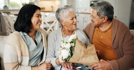 Birthday, flowers or gift with family on sofa in living room of home together for bonding or celebration. Bouquet, love or present with senior parents and daughter in apartment for event or milestone