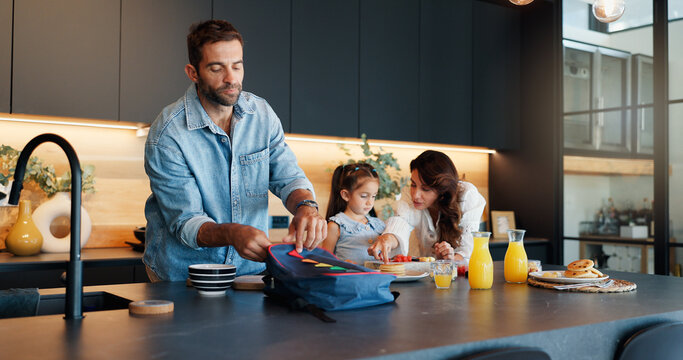 Parents, child and pack lunch in kitchen with healthy breakfast, getting ready and back to school. Mother, father and girl with family meal, nutrition food and prepare for kindergarten snack at house