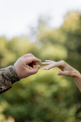 Photo isolated on green background. Military man puts on a wedding ring to a girl. Marriage during war