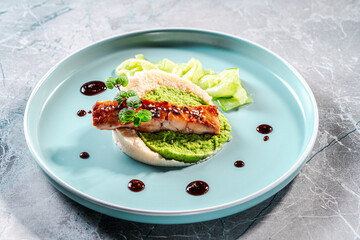 Cod fillet fried with spinach and broccoli and cauliflower puree sauce on a blue plate. The concept of healthy and dietary nutrition. Restaurant serving of the dish.