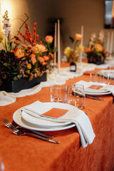 Luxury table setting for a celebration in a restaurant. Tones of orange and white. Tableware and catering for the holiday