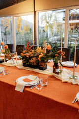 Luxury table setting for a celebration in a restaurant. Tones of orange and white. Tableware and catering for the holiday