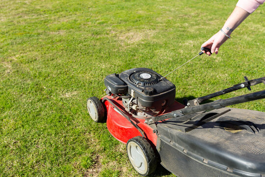 woman's hand pulling start rope on lawnmower