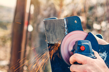Hand using angle grinder to cut metal with sparks in outdoor construction site