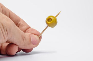 Hand presenting a green olive on a toothpick for a mediterranean appetizer