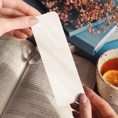 Woman holding a bookmark near an open book mockup
