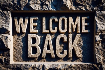 Obraz premium Weathered stone sign with deep grooves displaying the message 'Welcome Back' in bold letters, evoking a warm and inviting atmosphere