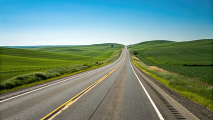 A smooth two-lane highway winding through rolling green fields under a clear blue sky, creating a tranquil, scenic drive with a limitless sense of exploration.