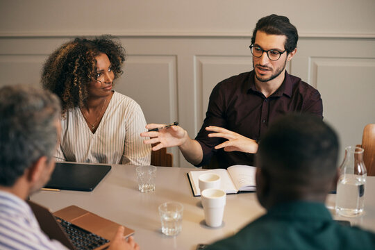 High angle view of young male creative professional explaining strategies to coworkers in office meeting room