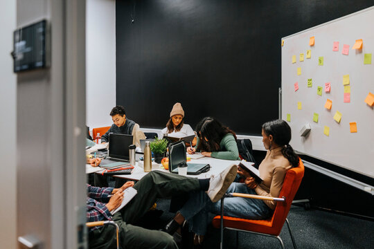 Female friends sitting and studying while sitting near table in classroom at college
