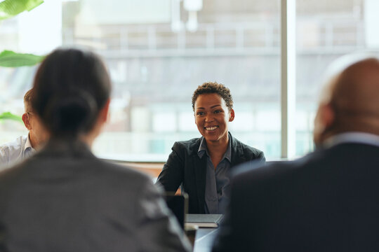 Smiling short haired female business professional at meeting with colleagues in office board room