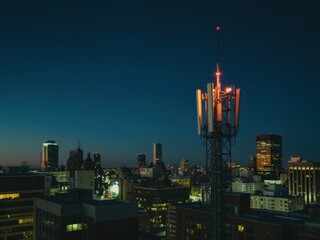 Fototapeta premium Cityscape illuminated at night showcasing skyline with modern buildings and a communication tower