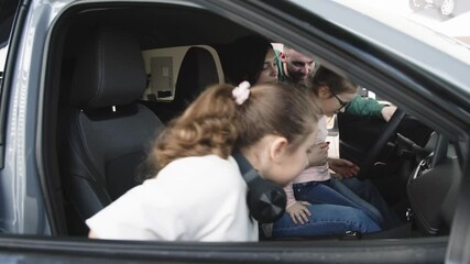 In a modern car dealership, a manager shows and advises a young family with children about buying or test driving a modern car. The concept of buying or leasing a new car.
