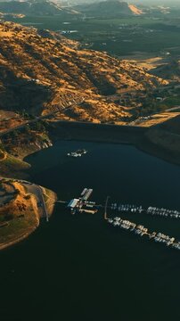Beautiful lake with dock for yachts and boats surrounded by mountains in California. Lovely green valleys behind the rocks at backdrop. Vertical video