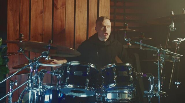 A talented drummer showcases impressive skills in a snug studio surrounded by wooden walls. The rhythm fills the air, creating an engaging atmosphere for all music lovers.
