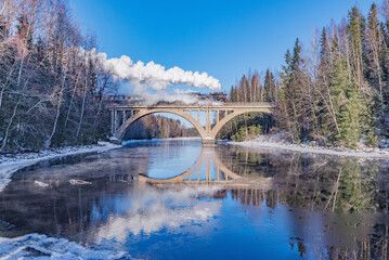 Steam train moves above the river.