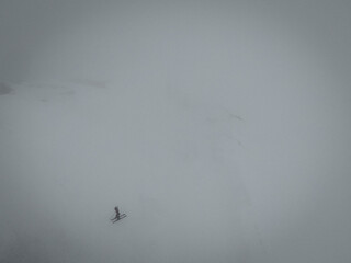Aerial Drone View of a Lone Skier Gliding Through Snow in a Foggy Winter Landscape, Surrounded by Mist and Silence