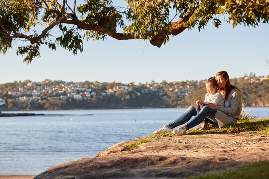 Mother and daughter sharing time together at headland over ocean