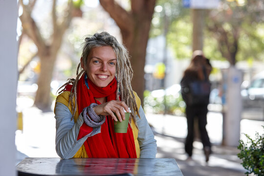 Young woman with dreadlocks smiling over coffee