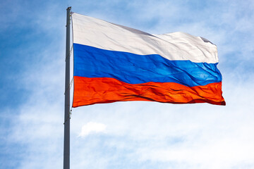 National flag of Russia against blue sky background. Russian flag waving in the wind
