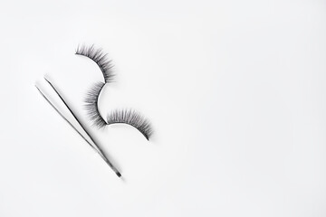 Pave eyelashes with forceps on white background. Procedure and makeup for eyelashes.