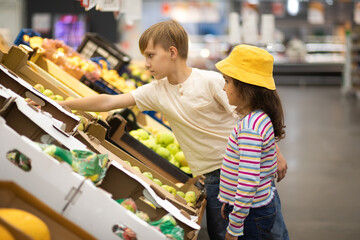 Kids little cute girl and teenager boy shopping for fresh organic fruits and vegetables in...