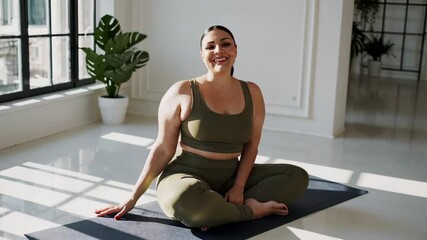 Wellness influencer plus size practicing yoga poses in a bright studio, promoting body positivity and mindfulness through her empowering online sessions