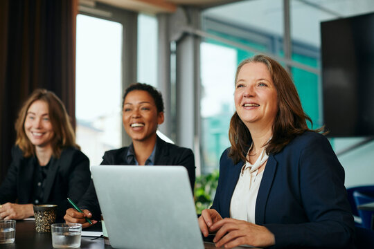Glada aff&auml;rskvinnor sitter p&aring; m&ouml;te i kontor