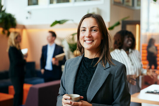 Portr&auml;tt av glad aff&auml;rskvinna som h&aring;ller i kaffemugg